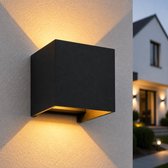 Zwarte kubusvormige buitenlamp met warme, aanpasbare lichtbundels op een stenen muur.