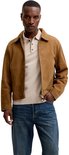 Man met beige gebreid poloshirt en bruine suède jas, met donkerblauwe jeans.