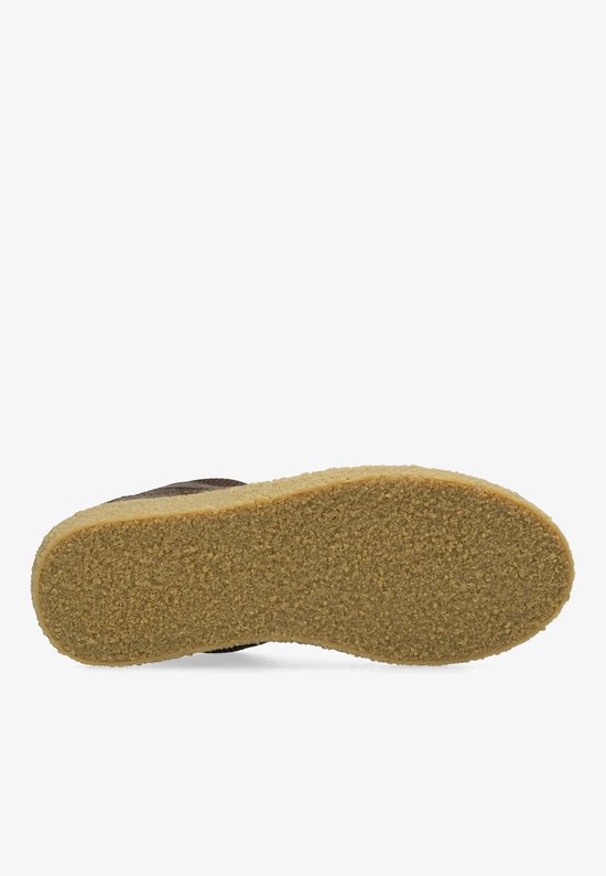 Onderkant van een donkerbruine suède sneaker met een crèmekleurige, gestructureerde zool.