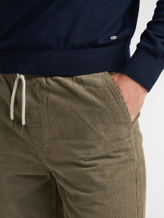 Detail van de elastische tailleband met trekkoord van een olijfgroene corduroy broek.