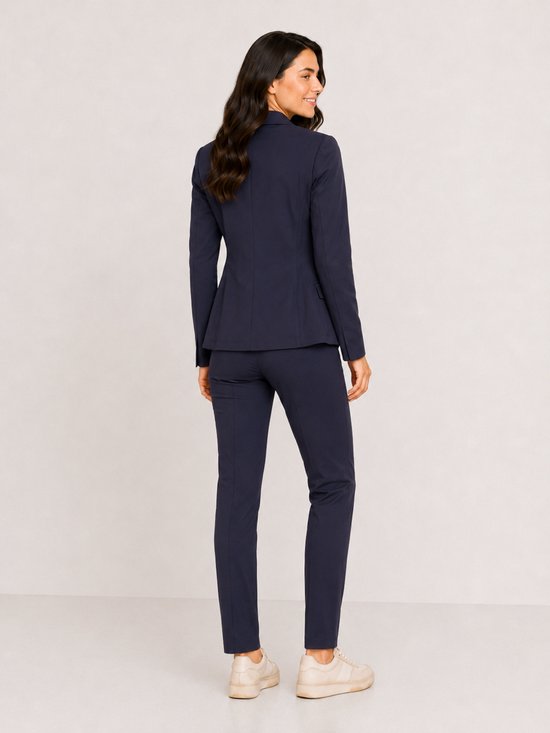 Vrouw in marineblauw pak van Mi Piace, met blazer en broek. De blazer is aan de achterkant te zien.