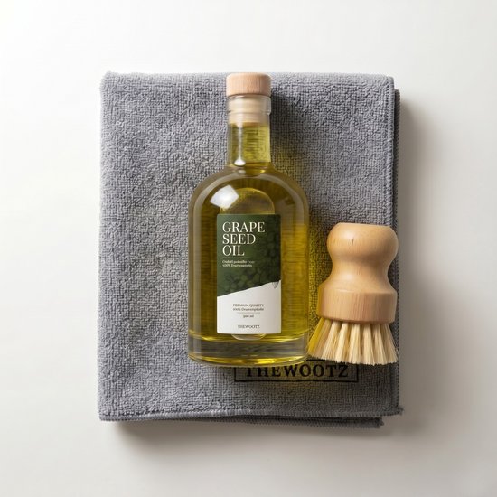 Glazen fles druivenpitolie met groen etiket op grijze theedoek met houten borstel.