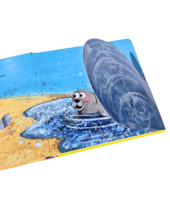 Een open Gottmer flappenboek 'Coco op het strand' toont een zeehond die spettert in het water. Er is een groot, rond flapje met de tekst 'OINK' erop.