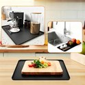 Zwarte siliconenmat die wordt gebruikt onder een koffiezetapparaat, bij een gootsteen en met een snijplank.