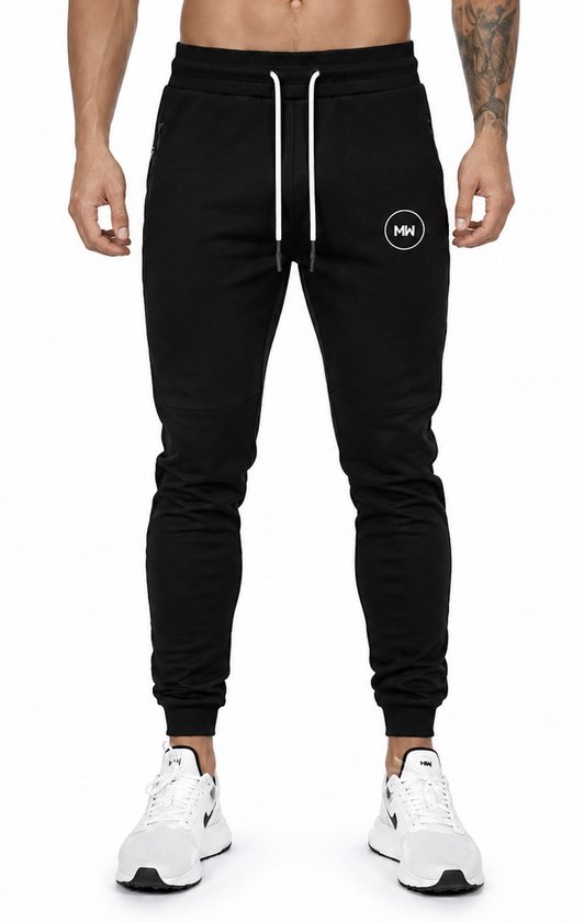 Een man in een zwarte trainingsbroek met trekkoord en witte sneakers.