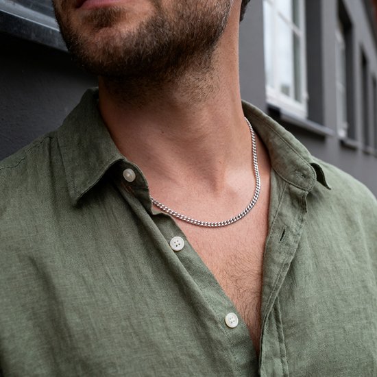 Man met groen hemd en zilverkleurige schakelketting om de nek.
