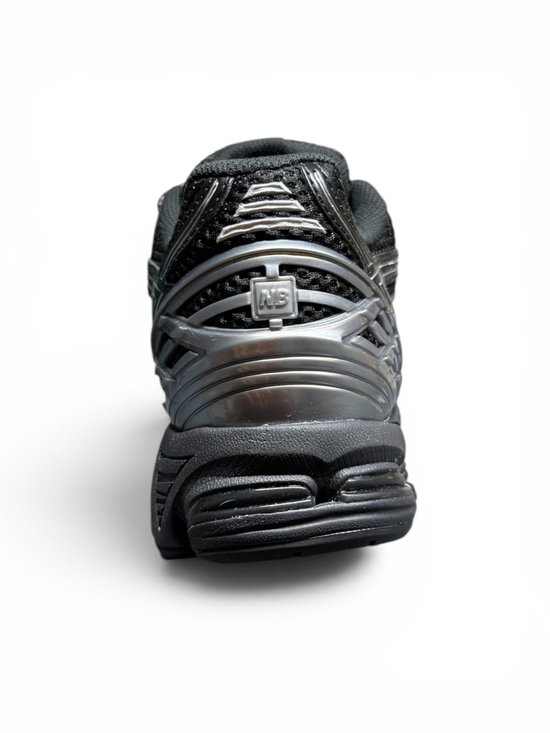 Achterkant van een zwarte New Balance 1906R sneaker met zilveren details.