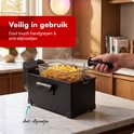 Zwarte friteuse met anti-slip voetjes, cool touch handgrepen, en een mandje vol goudbruine frietjes.