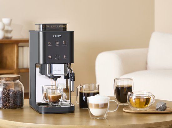 Zwarte Krups Coffee Crush koffiemachine in keukenomgeving, met koffiebonen, espresso, latte en thee.
