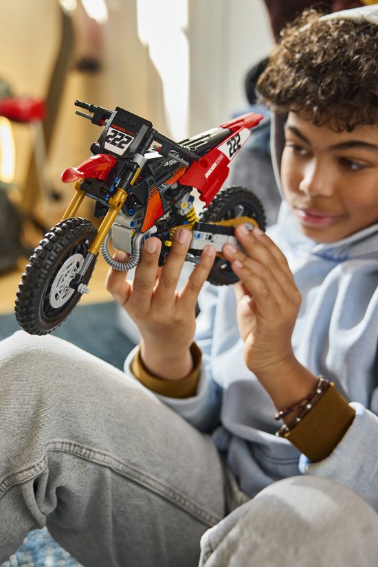 Jongen houdt een gedetailleerde LEGO Technic Ducati motorfiets vast.