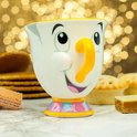 Mug blanc avec le visage de Chip, anse orange et base colorée, entouré de pâtisseries.
