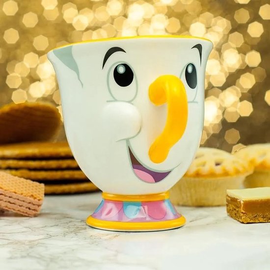 Mug blanc avec le visage de Chip, anse orange et base colorée, entouré de pâtisseries.