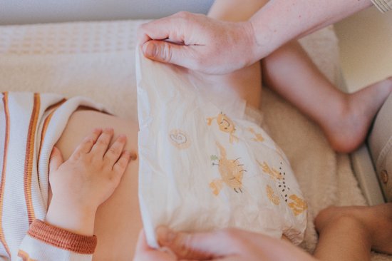 Baby's buik met luier met krabbenprint, wordt verschoond door een volwassene.