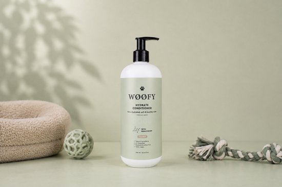 WØØFY Hydrate Conditioner fles met pompdispenser, omringd door een hondenmand, bal en touwspeeltje.