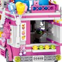 Detail van de zijkant van een roze bouwsteen foodtruck met 'Cake' opschrift, cupcakes en ballonnen aan de voorkant.