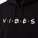 Detailopname van de 'VIBES' print op een zwarte hoodie.