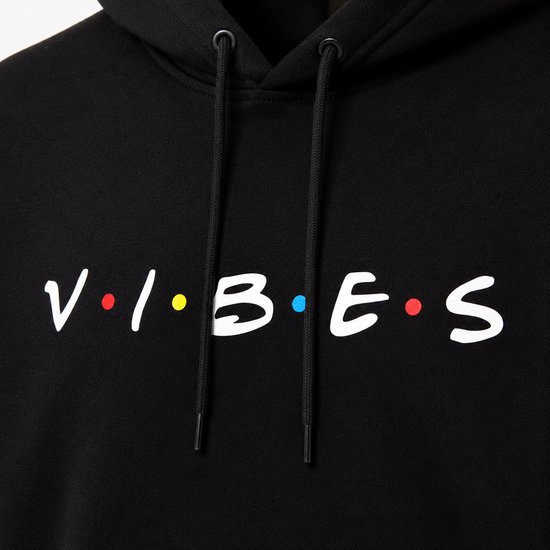 Detailopname van de 'VIBES' print op een zwarte hoodie.
