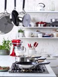 Een keuken met KitchenAid pannen aan haken en op het fornuis.