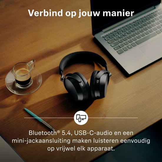Zwarte Sennheiser koptelefoon op een houten tafel naast een laptop en een kopje koffie. Verbinding via Bluetooth, USB-C of mini-jack.