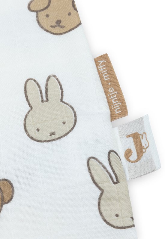 Detail van een witte hydrofiele stof met een print van bruine beren en konijntjes. Met Jollein en Nijntje label.