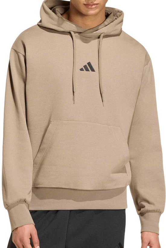 Homme portant un sweat à capuche beige avec logo Adidas noir et poche kangourou.