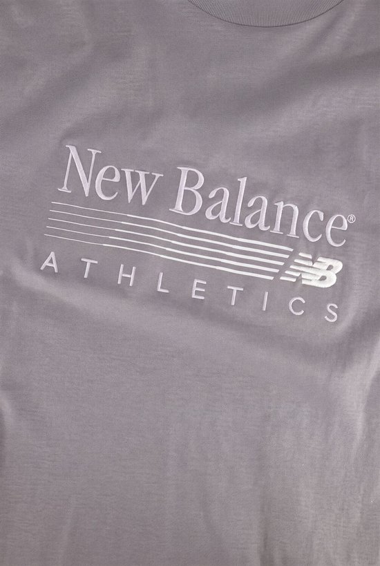 Detailopname van het witte New Balance Athletics logo op een grijze oversized T-shirt.