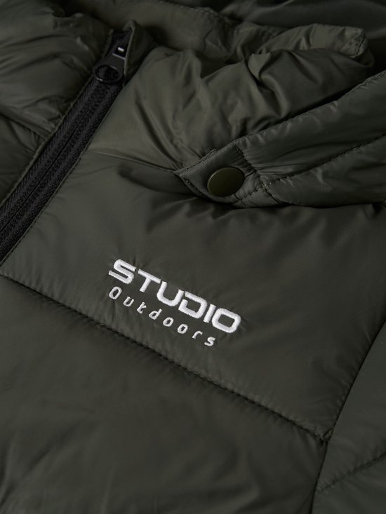 Detail van een donkergroene jas met de tekst "STUDIO Outdoors" geborduurd op de linkerborst.