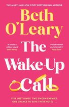 Boek 'The Wake-Up Call' van Beth O'Leary, met rode kaft, gouden ringen en tekst over een hotele. 'Vijf verloren ringen. Twee gezworen vijanden. Één kans om hun hotel te redden...'