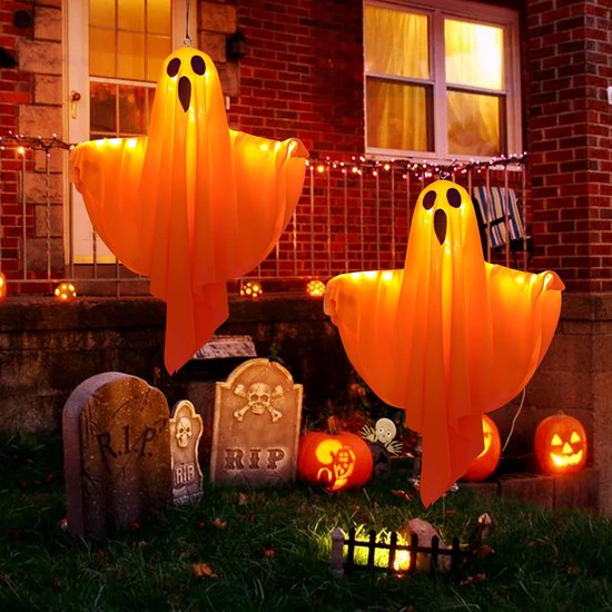 Twee oranje spoken met LED-verlichting hangend voor een bakstenen huis met Halloween-decoraties.