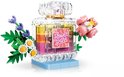 Flacon de parfum transparent avec couches jaunes, oranges et roses, étiquette 'Flower Spark', fleurs roses et petites fleurs violettes.