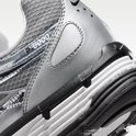 Close-up van de achterkant en zijkant van de grijze Nike P-6000 sneaker. Zwarte zool met witte lagen en 'P-6000' op de zijkant.