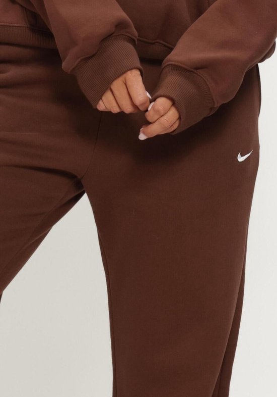 Detailopname van een vrouw die een bruine Nike joggingbroek draagt, met de focus op de manchetten.