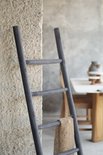 Donkergrijze teakhouten decoratieve ladder met 5 sporten, met een stuk jute stof erop.