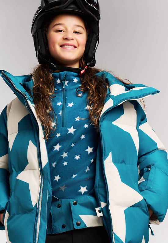 Meisje in blauwe winterjas met sterrenprint, hoge kraag en skihelm.