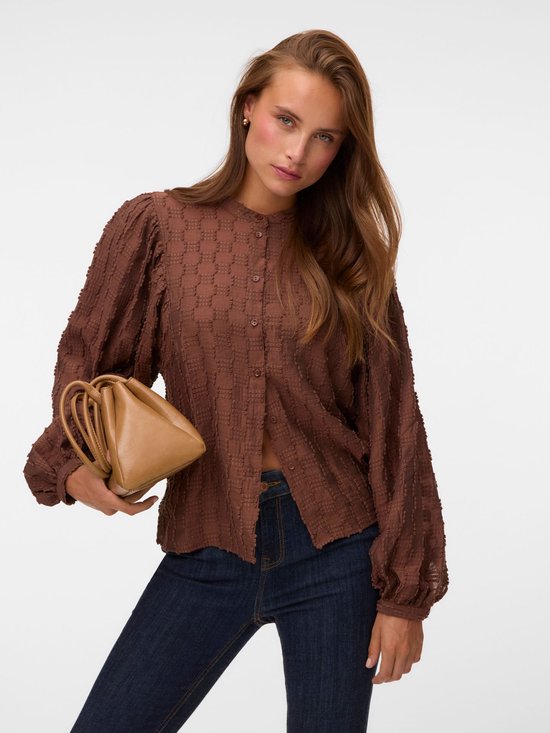 Model met bruine blouse met vierkante textuur en pofmouwen, donkere jeans en bruine tas.