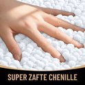 Close-up van een vinger die in een dikke, zachte, witte chenille badmat drukt.