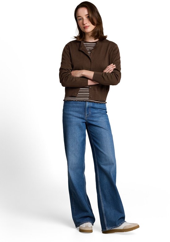 Model draagt een bruine vest met ronde hals, gestreepte top en jeans. Armen over elkaar.