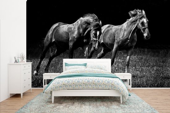 Zwart-wit muurschildering van twee rennende paarden achter een wit bed in een minimalistische slaapkamer.