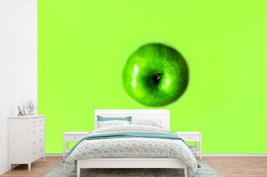 Chambre avec papier peint vert vif et une grande pomme Granny Smith au-dessus d'un lit et d'une commode blancs.
