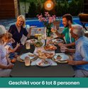 Familie geniet van diner aan zwarte tafel. "Geschikt voor 6 tot 8 personen".