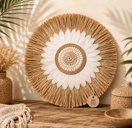Ronde wanddecoratie met naturel veren, witte veren en middenstuk met kralen en schelpen. Met label 'Pure Bali Living'.
