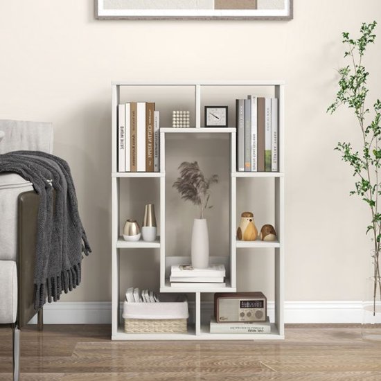 Witte geometrische boekenkast met open vakken, gevuld met boeken, vazen, een radio en decoraties.