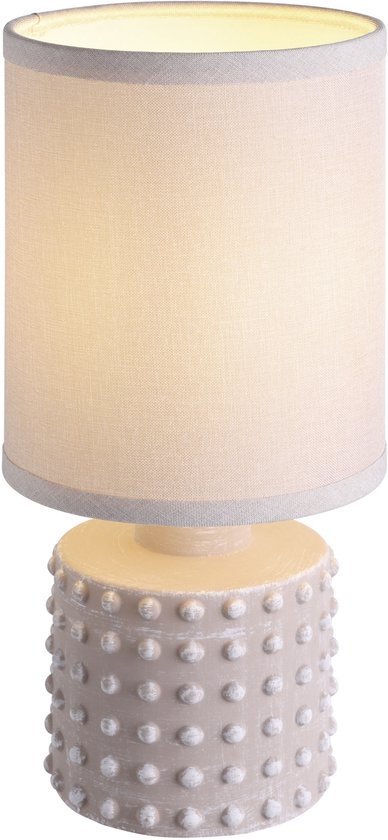 Lampe de table beige avec abat-jour cylindrique éclairé et base décorative à picots.