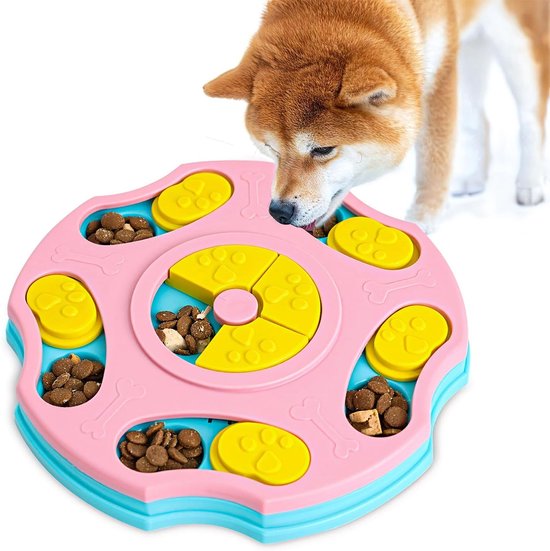 Shiba Inu hond eet brokjes uit een roze en blauw interactief voerspeelgoed met gele compartimenten.
