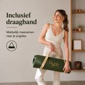 Vrouw in beige outfit houdt een donkergroene yogamat met gouden print en draagband vast.
