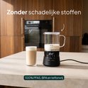 Zwarte melkopschuimer met glazen kan, 100% PFAS, BPA en teflonvrij, naast een glas met melkschuim.