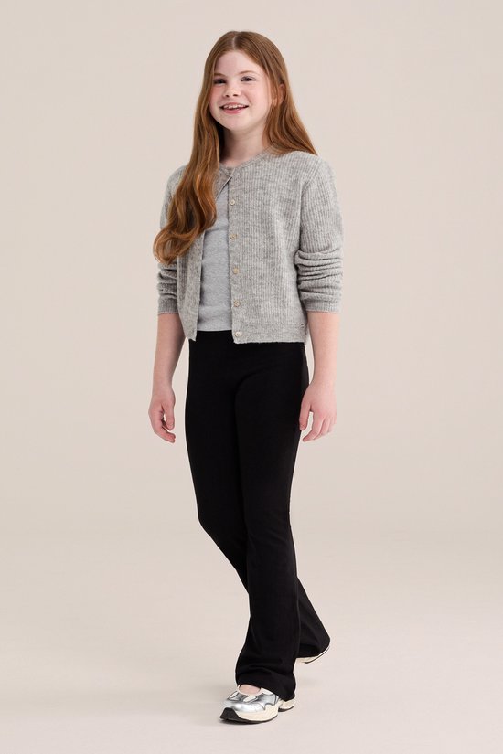 Meisje met lang rood haar draagt een zwarte flared legging, een grijs T-shirt en een grijs vest met knopen.