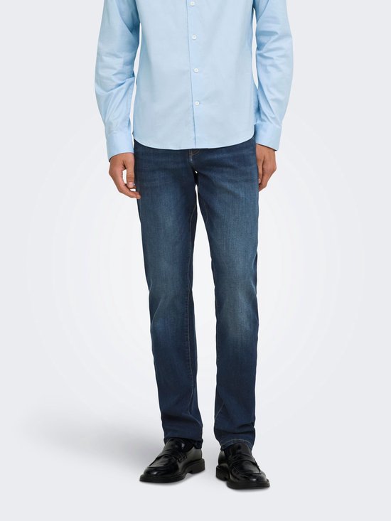 Onderlichaam van een man in lichtblauwe blouse en donkere jeans.