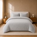 Grijze teddy fleece dekbedovertrek en kussens op een bed in een slaapkamer met natuurlijke tinten.