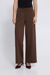Model draagt een bruine wijde broek met hoge taille, gecombineerd met hakken.